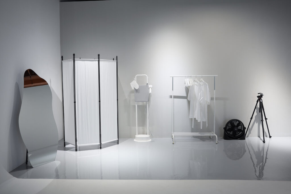White studio shoot area with styling rack and camera tripod
